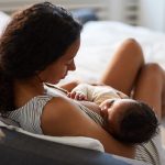 Peaceful,Loving,Young,African,Mother,Sitting,On,Bed,And,Leaning