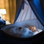 Adorable,Baby,Sleeping,In,Blue,Bassinet,With,Canopy,At,Night.