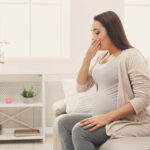 Young,Vomiting,Woman,Sitting,On,Sofa.,Pregnant,Lady,Suffering,With