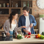 Happy,Couple,Cooking,Dinner,Together,In,Their,Loft,Kitchen,At