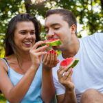 Couple,Sitting,On,A,Picnic,Blanket,And,Eating,Watermelon