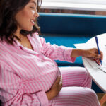 Happy,Pregnant,Woman,Writing,In,Her,Pregnancy,Calendar,,At,Home.