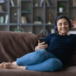 Happy,Millennial,Indian,Woman,Relax,On,Couch,In,Living,Room
