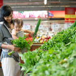 Beautiful,Asian,Woman,Carrying,Her,Baby,While,Shopping,In,Grocery
