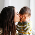 Portrait,Of,Young,Mother,Kissing,Her,Little,Son,In,Forehead