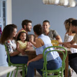 Friends,With,A,Child,Sit,Talking,Around,A,Dining,Room