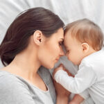 Motherhood.,Mother,And,Baby,Together,Holding,Hands,Sleeping,Lying,On