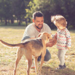 Father,And,Toddler,Feeding,And,Walking,With,Dog