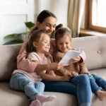 Happy,Family,Young,Mother,Babysitter,Hold,Read,Book,Relax,Embrace