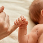faceless-mother-with-naked-baby-infant-holding-mommy-s-finger-mum-spending-time-with-her-tiny-child-light-background