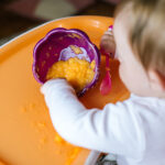 Young,Dirty,Baby,Girl,Eating,In,High,Chair