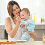 Mother,Feeding,Baby,With,Spoon,Indoors