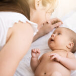Young,Mother,Holding,A,Newborn,Baby.,Mom,Talks,And,Laughs