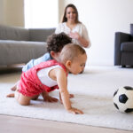 Cute little kids crawling on carpet and playing with soccer ball