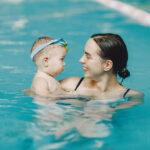 Mother and little son enjoying swimming in a swimming pool