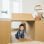 smiling-baby-toddler-inside-open-cardboard-box-home