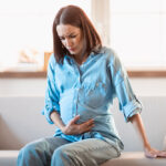 Expectant,Woman,Experiencing,Braxton,Hicks,Contractions,,Touches,Her,Belly,In