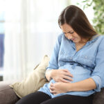 Pregnant,Woman,Suffering,Belly,Ache,Sitting,On,A,Couch,In