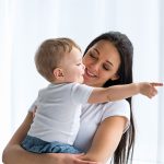 Portrait,Of,Smiling,Mother,With,Adorable,Baby,In,Hands,Pointing